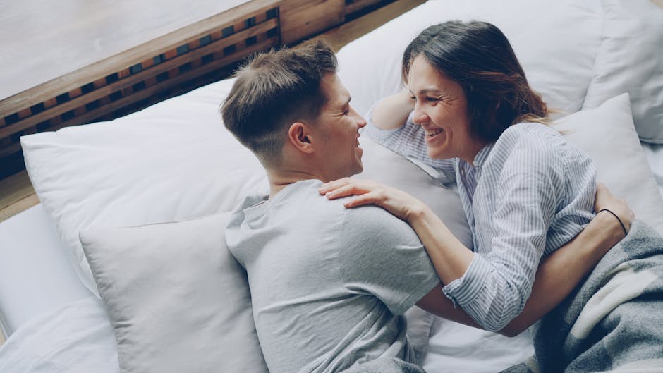 A joyful moment of a couple laughing and embracing on a bed, conveying love and happiness.