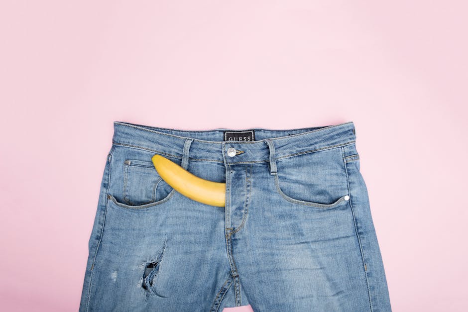 Fun and conceptual still life photo featuring a banana in blue jeans against a pink background.